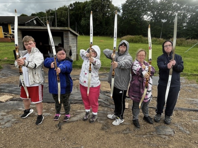 Group of adults with Down syndrome holding archery bows.